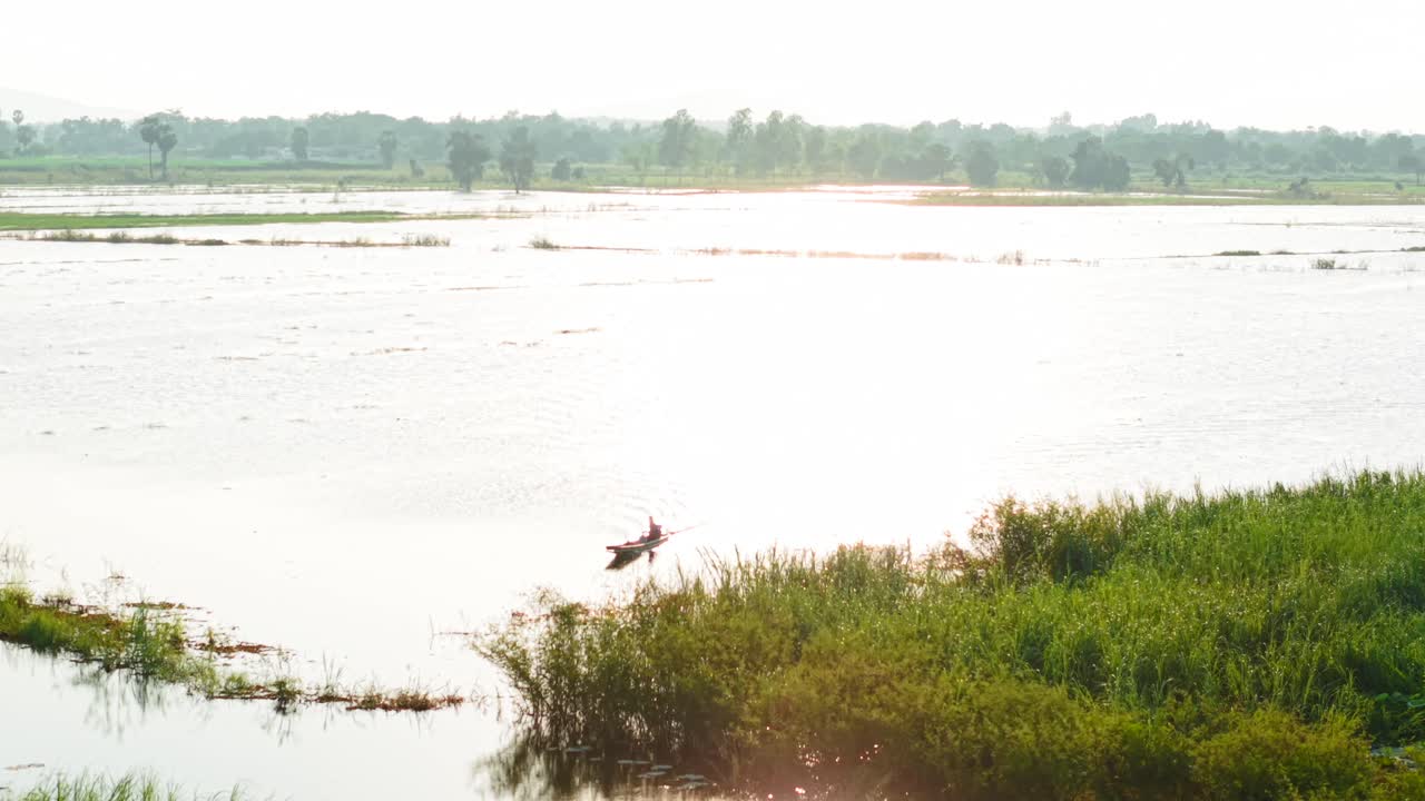 A person in a boat on a tranquil lake, surrounded by lush vegetation