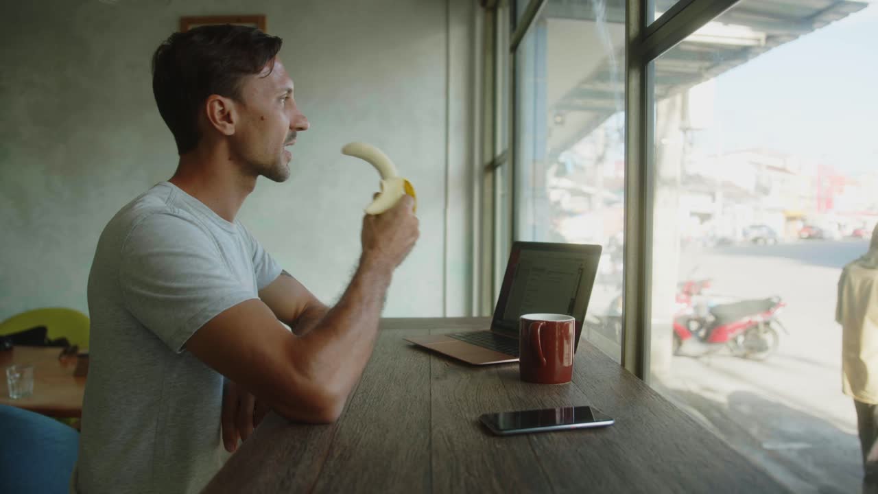 Man Eating Banana and Working in a Cafe
