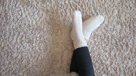 woman's legs in white socks on a fluffy carpet