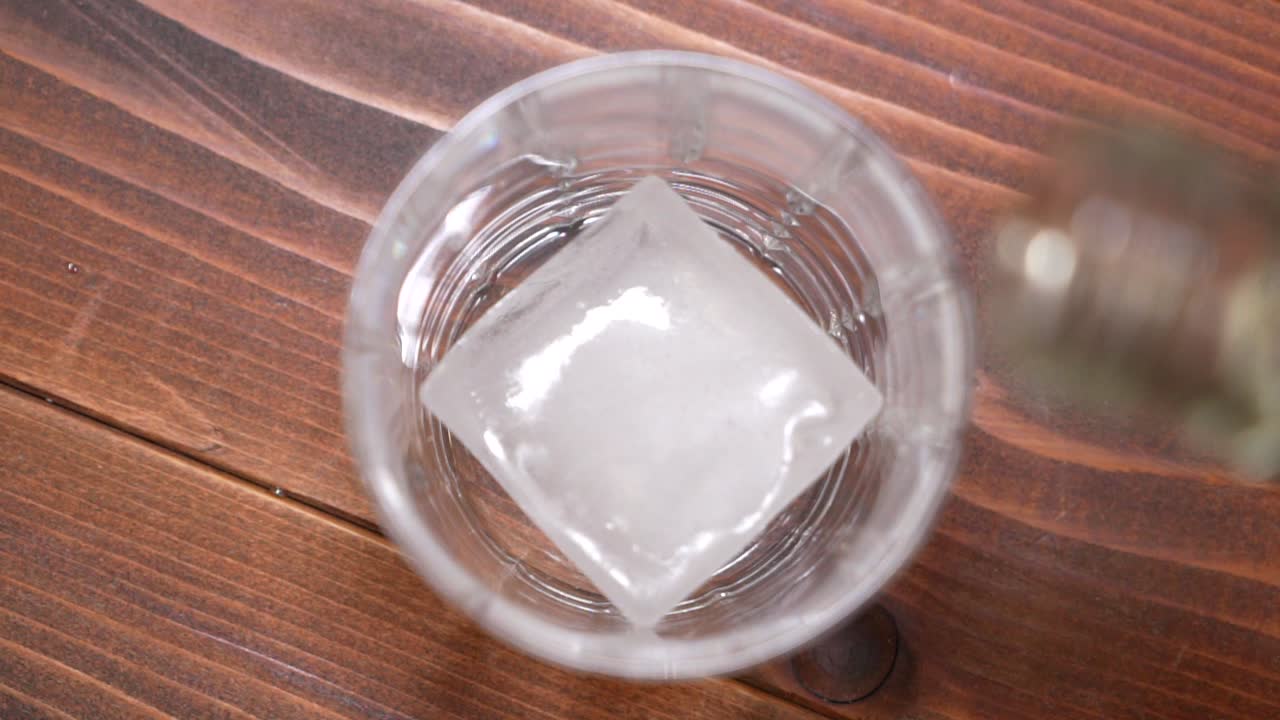 whisky que se vierte en un vaso con hielo en cámara lenta hd