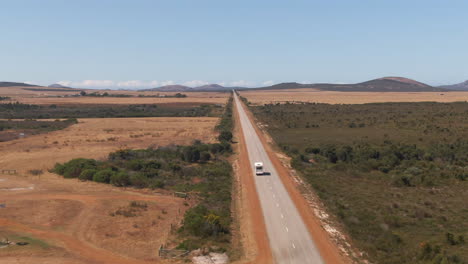 Aerial-tracking-shot-of-Van-on-empty-straight-road-near-Margaret-River,-WA,-Australia