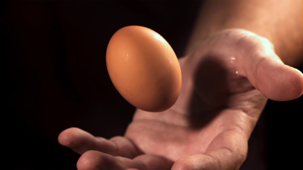 Man's Hand Tossing and Catching a Single Brown Egg