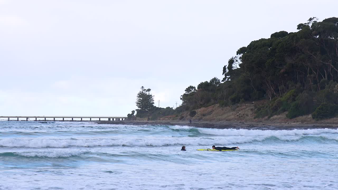 Surfers riding waves near a scenic pier