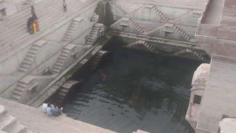 a swimmer surfaces from the depths of a beautiful step well in jodhpur india known as toorji ka jhalra or toorji’s step well