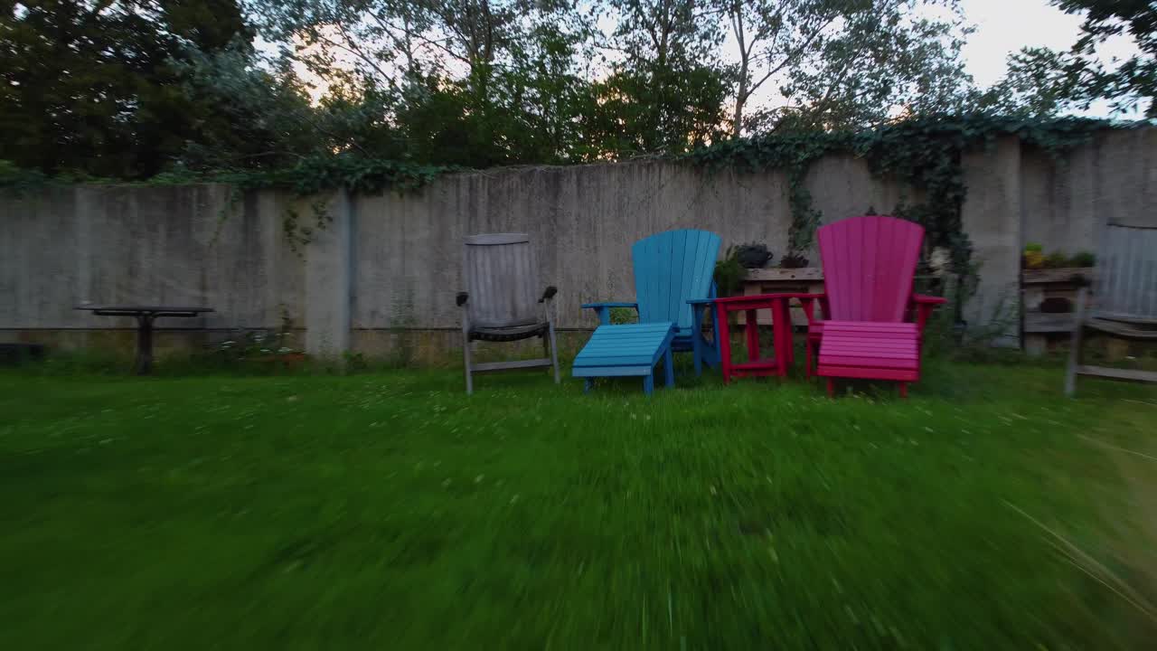 muovendosi molto rapidamente attraverso il giardino esterno della casa sul lato c'è una gomma appesa a una corda legata a un albero come un cerchio diversi sedili e tavolo nel luogo diretto verso la colorata sedia da spiaggia blu