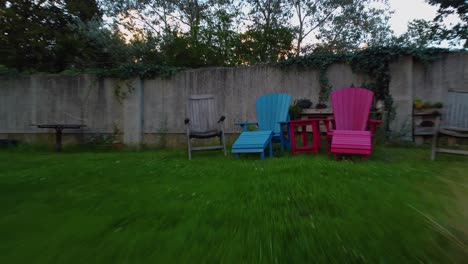 moviéndose muy rápidamente a través del jardín exterior de la casa en el lado es un neumático colgando de una cuerda atada a un árbol como un aro diferentes asientos y mesa en el lugar dirigiéndose hacia colorida silla de playa azul
