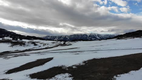 Low-flying-drone-shot-of-dramatic-clouds-and-mountain-peaks-during-winter