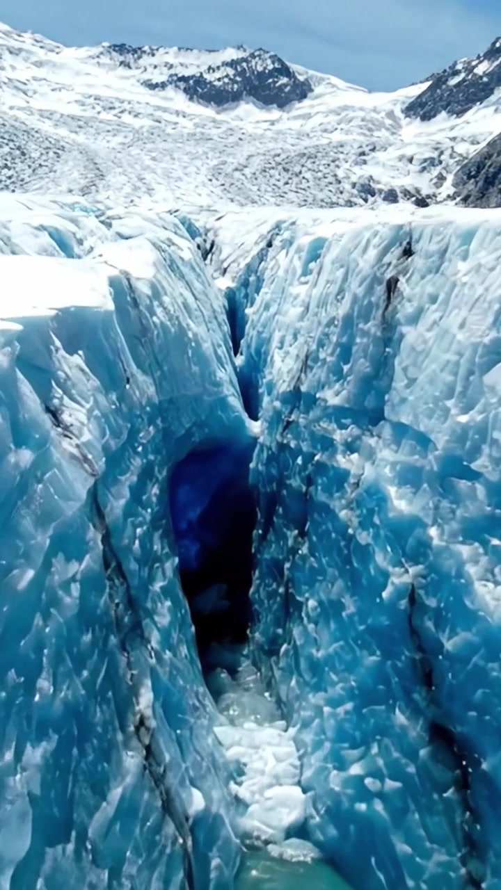Una splendida crepa glaciale che rivela il ghiaccio blu profondo e lo splendore naturale in un maestoso paesaggio artico, catturata da due prospettive