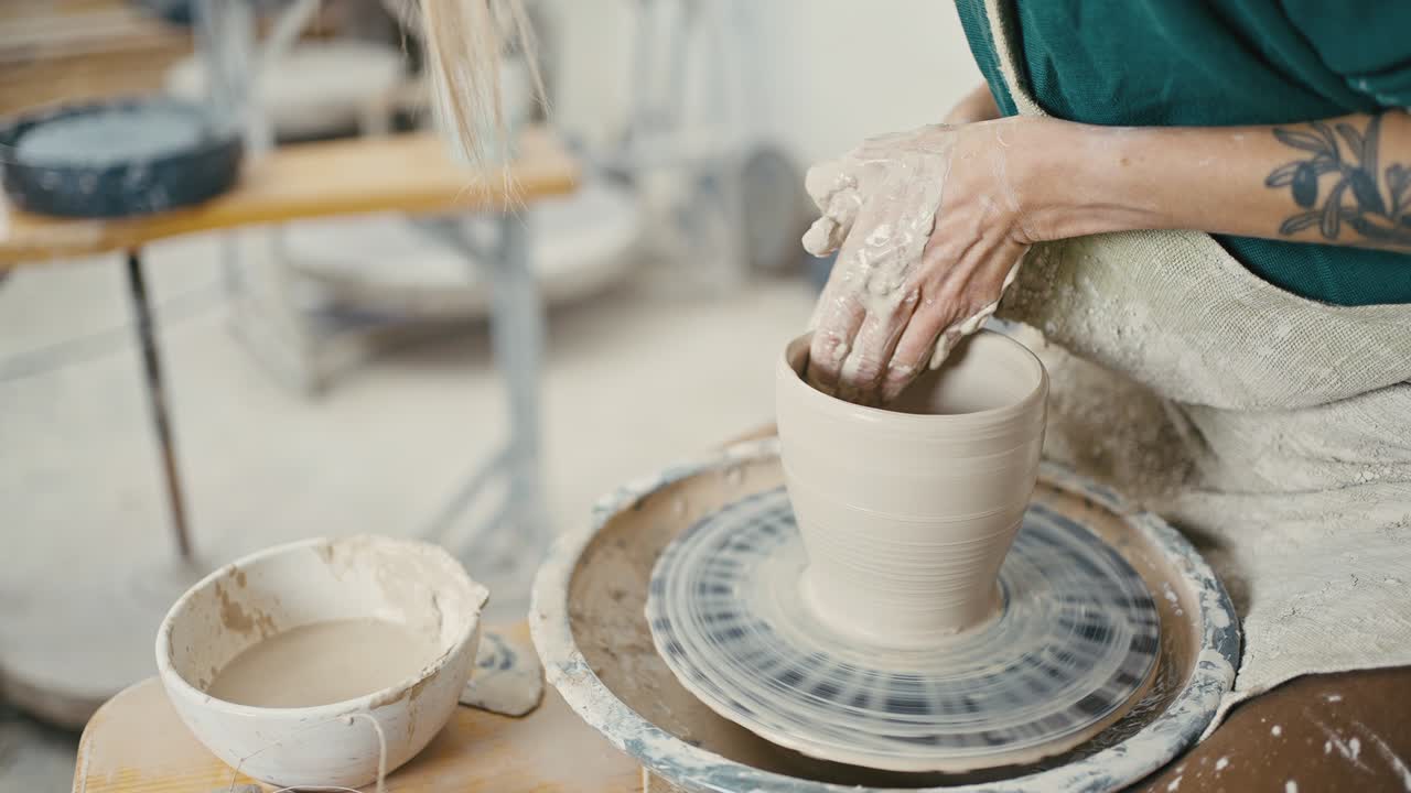 도자기 제작 과정: 여성 도자기가 도자기 바에 세라 꽃병을 조각하는 클로즈업, 추적, 느린 동작