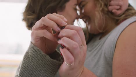 portrait of happy caucasian lesbian smiling, embracing and holding key to their new home