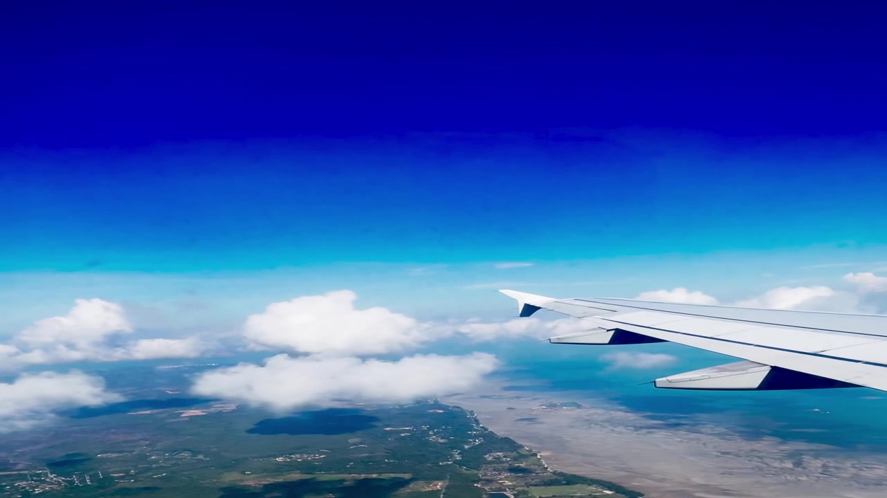 Vista aerea dell'ala di un aereo sopra la costa e le nuvole