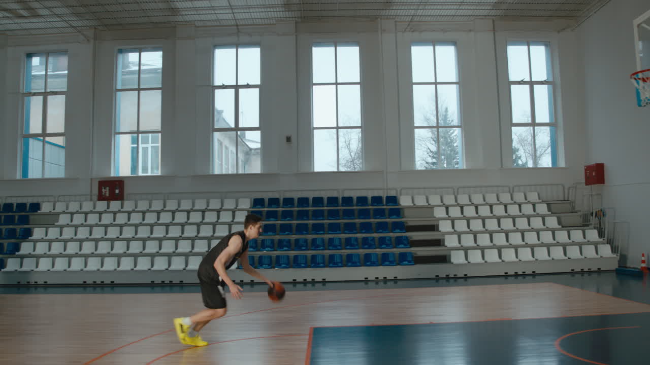 High school team basketball player practicing dunks indoors. 4K UHD
