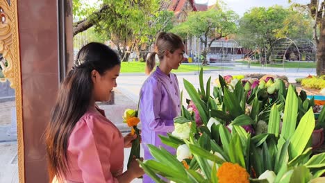 women preparing floral offerings at a thai temple