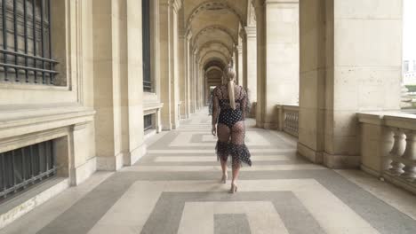 woman in a polka dot dress walking through parisian arcades