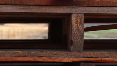 camera moves parallel to wood pallet looking through the gaps into farming fields