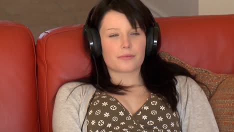 mujer relajada escuchando música sentada en el sofá
