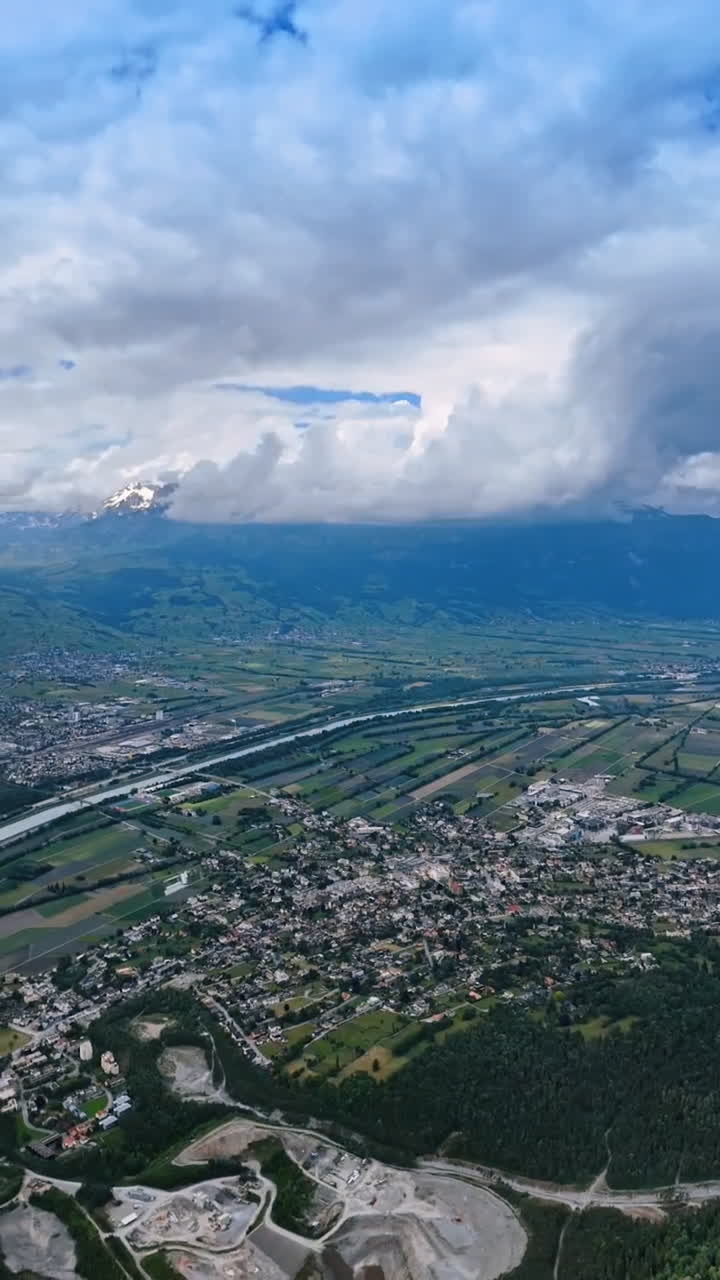 The Rhine crossing the scenery of Lichtenstein from top. Beautiful mountains surrounding the picturesque urban area. Top view. Vertical video.