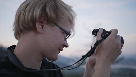 Close-up-orbit-of-young-man-taking-photo-with-digital-camera-at-sunset