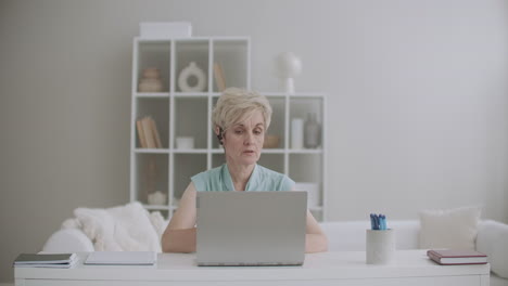 serious woman is talking by videocall on laptop teacher is communicating with student online during pandemic of coronavirus