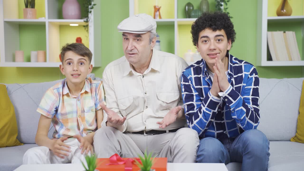 할아버지는 손자들과 함께 tv를 보고 있습니다.