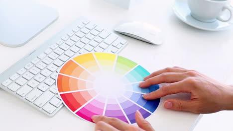 diseñador gráfico usando la rueda de colores en su escritorio