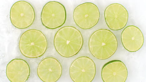 on a white background sliced pieces of lime are sprinkled with water. juicy fresh lime in slow motion. lots of lime slices.