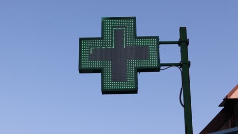 Illuminated-pharmacy-green-cross-sign-in-Bologna,-Italy