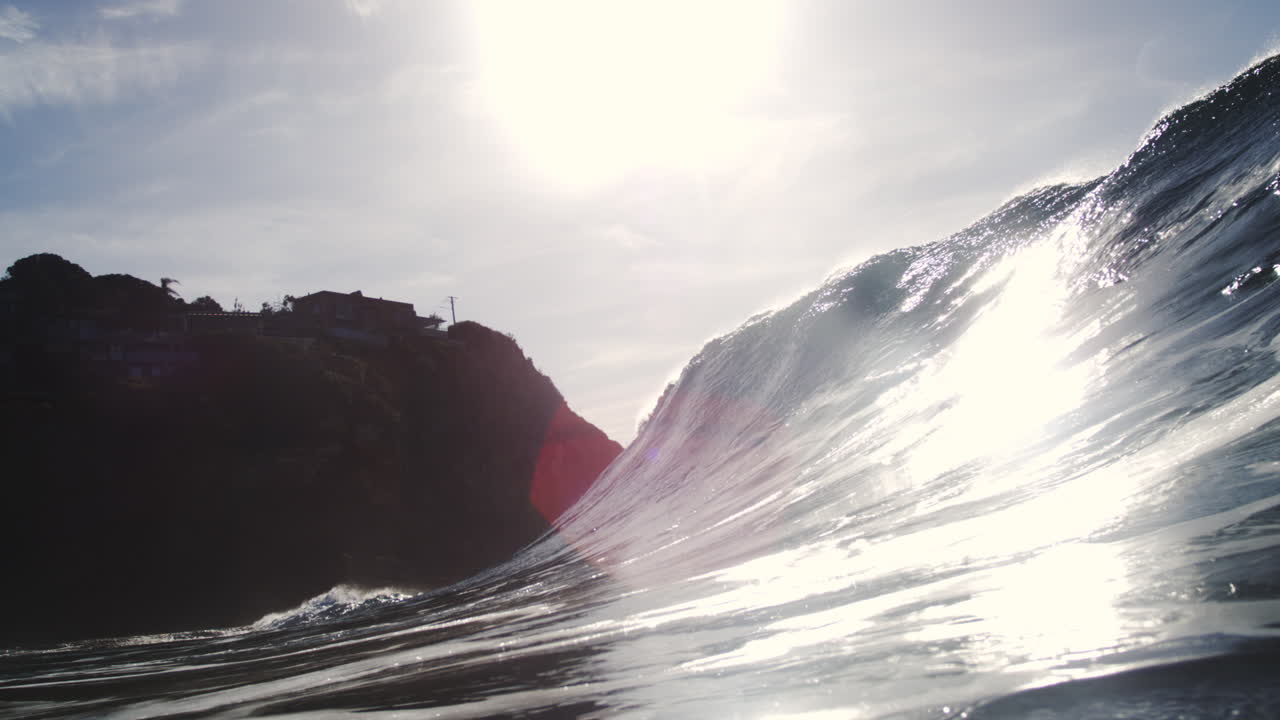 Backlit ocean wave curls and crashes in cinematic slow motion