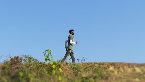 Ein-Junger-Mann-In-Einem-Grünen-Langarmshirt-Läuft-Mit-Maske-Während-Der-Pandemie-In-Bangladesch-An-Einem-Sonnigen,-Wolkenlosen-Tag