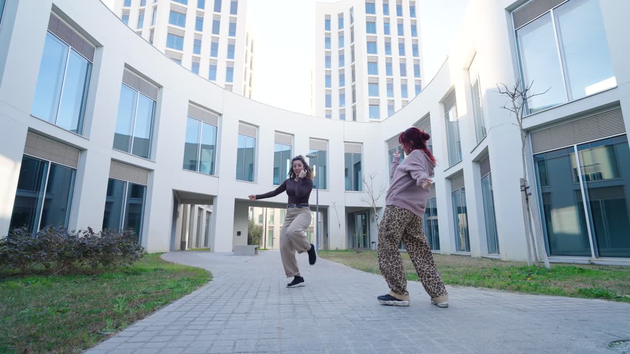 Young women dancing outside modern building