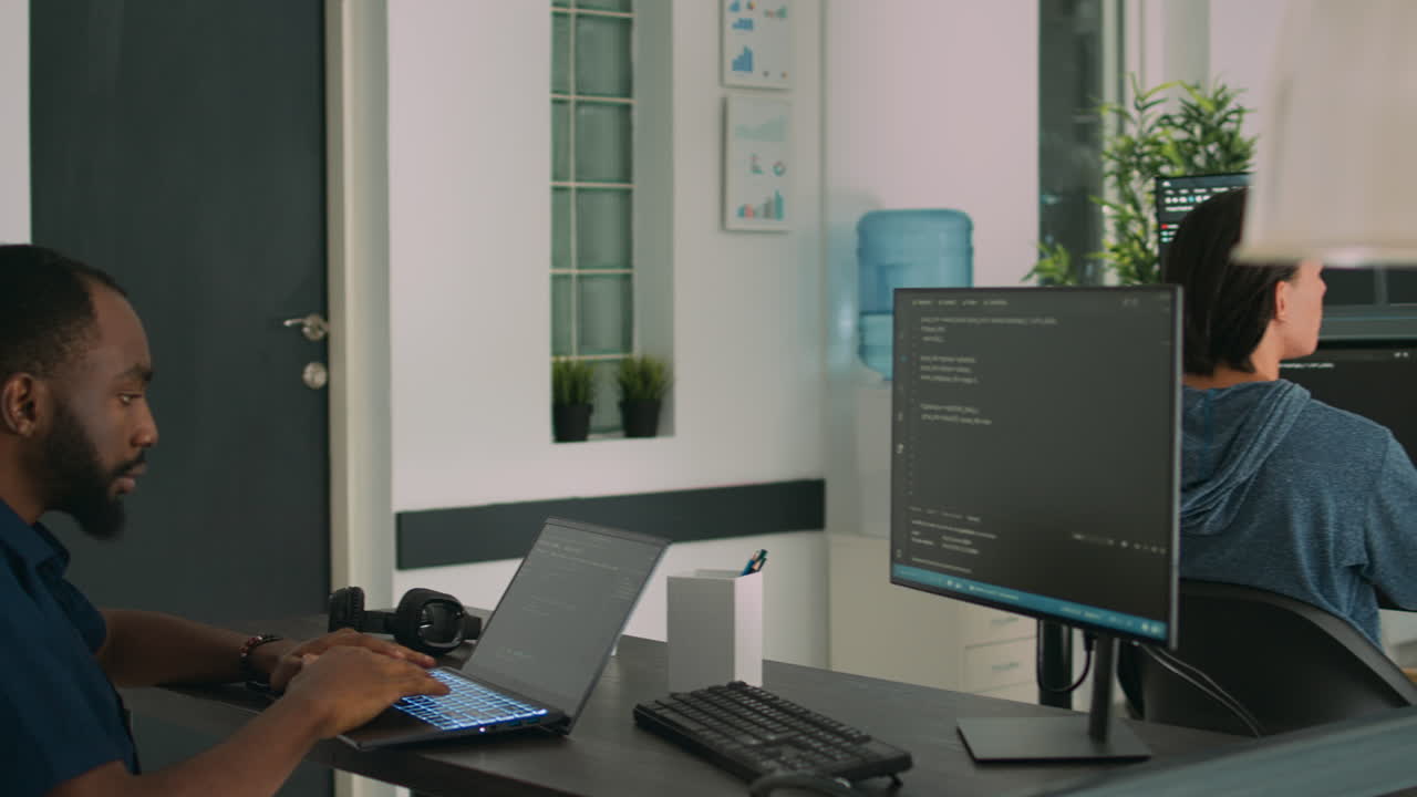 African american developer using laptop to write code and display system information