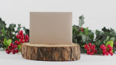 video de decoraciones de navidad de bayas y hojas con tarjeta blanca en blanco en tronco, con fondo blanco