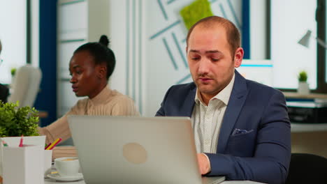 busy business man using laptop typing sitting at conference table in broadroom