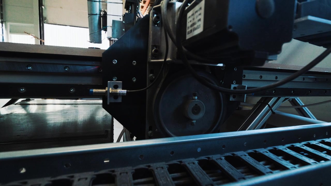 Detail CNC kabelového řetězu a strojní kolejnice uvnitř profesionální dřevozpracující dílny.