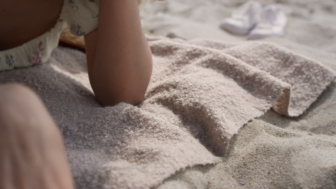 연약한 여성의 손이 밝은 노란색 매니큐어와 함께 해변 모래를 만지고 있습니다.