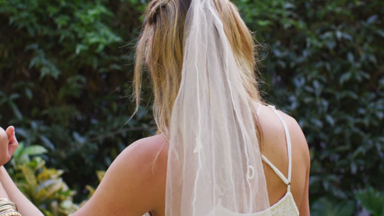 행복 한 다양 한 여성 부부 가 손 을 잡고 정원 에서 춤 을 추고 있다