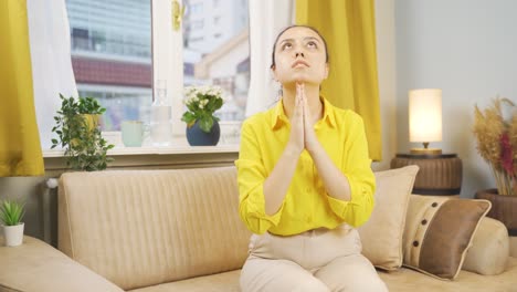 christian young woman praying in front of the window.