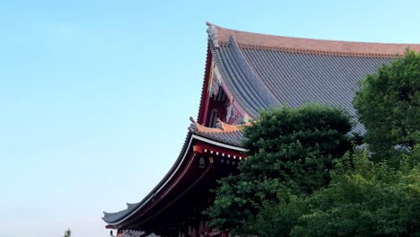 Traditional-Japanese-temple-roof-surrounded-by-lush-green-trees-on-a-clear-day