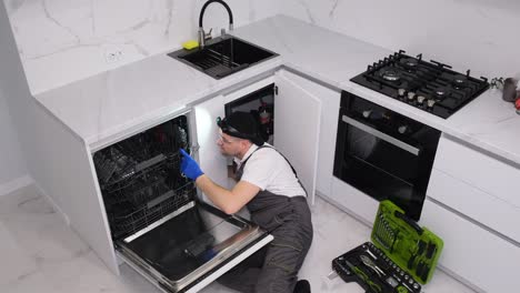a plumber works lying on the floor in the kitchen he installs a sink the work of a plumber