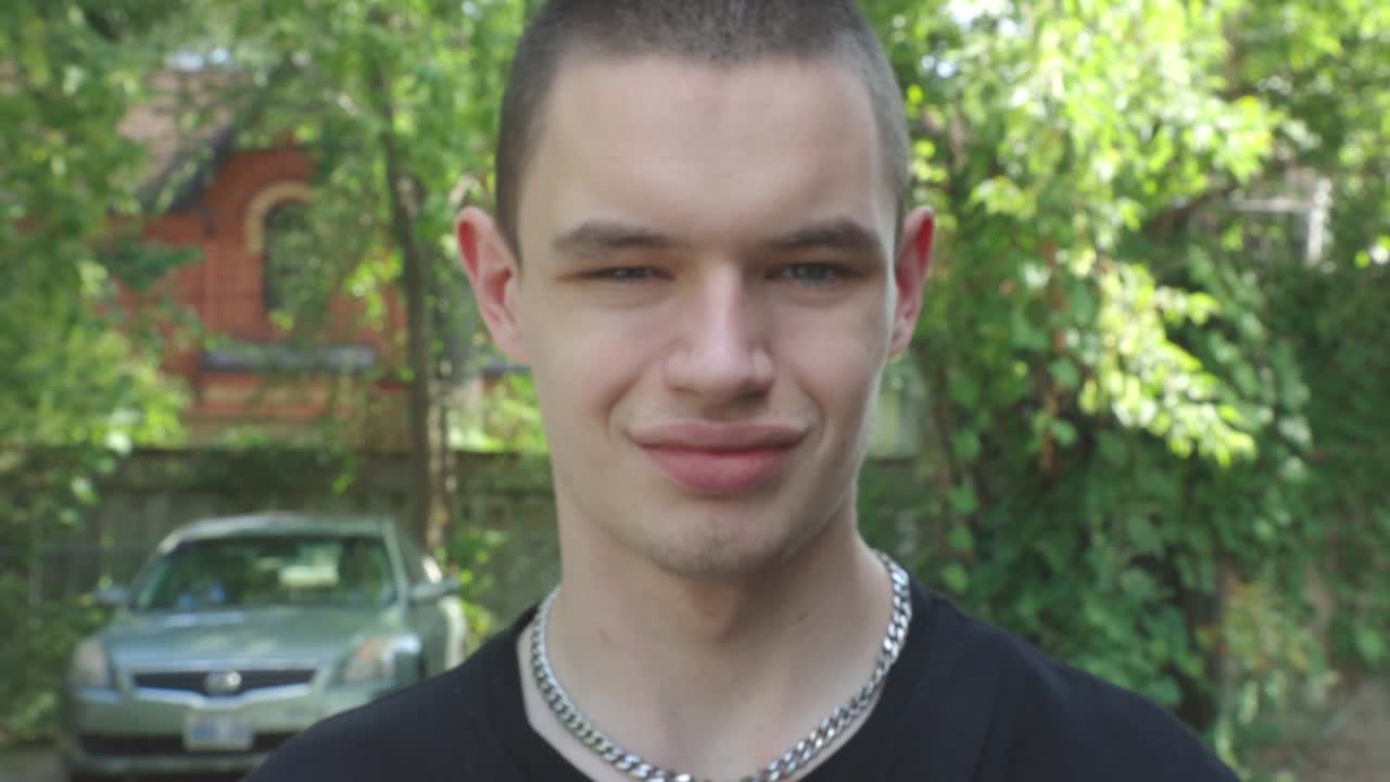 Young Caucasian Man Smiling And Winking In Front Of A Camera . - over the shoulder shot