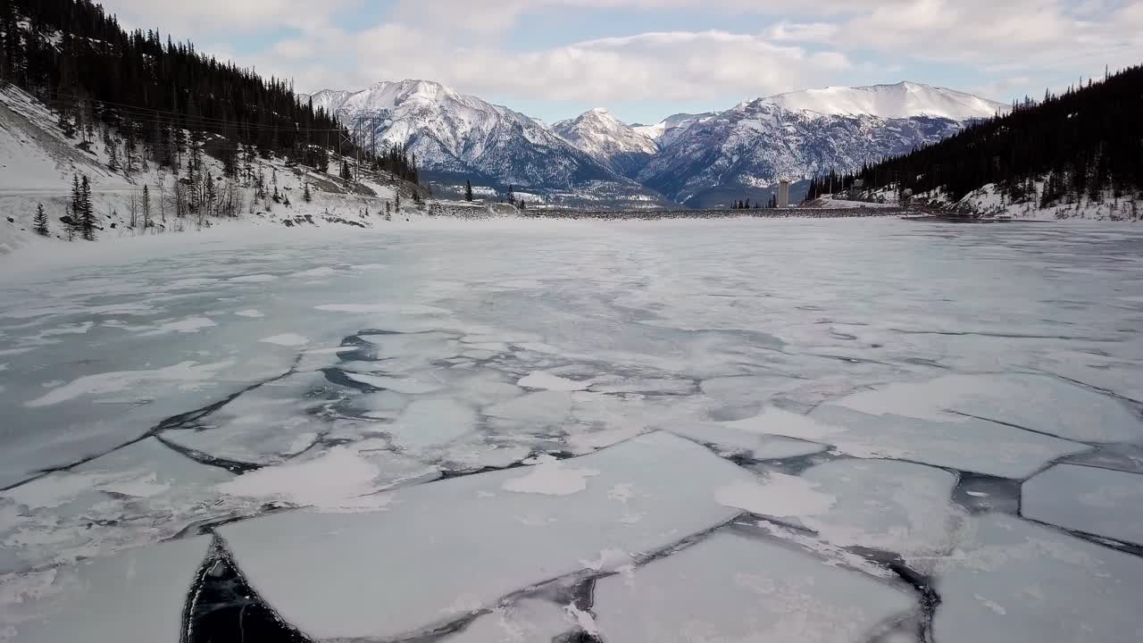 The ice covered lake in the Spray Lakes Reservoir during winter - aerial descent