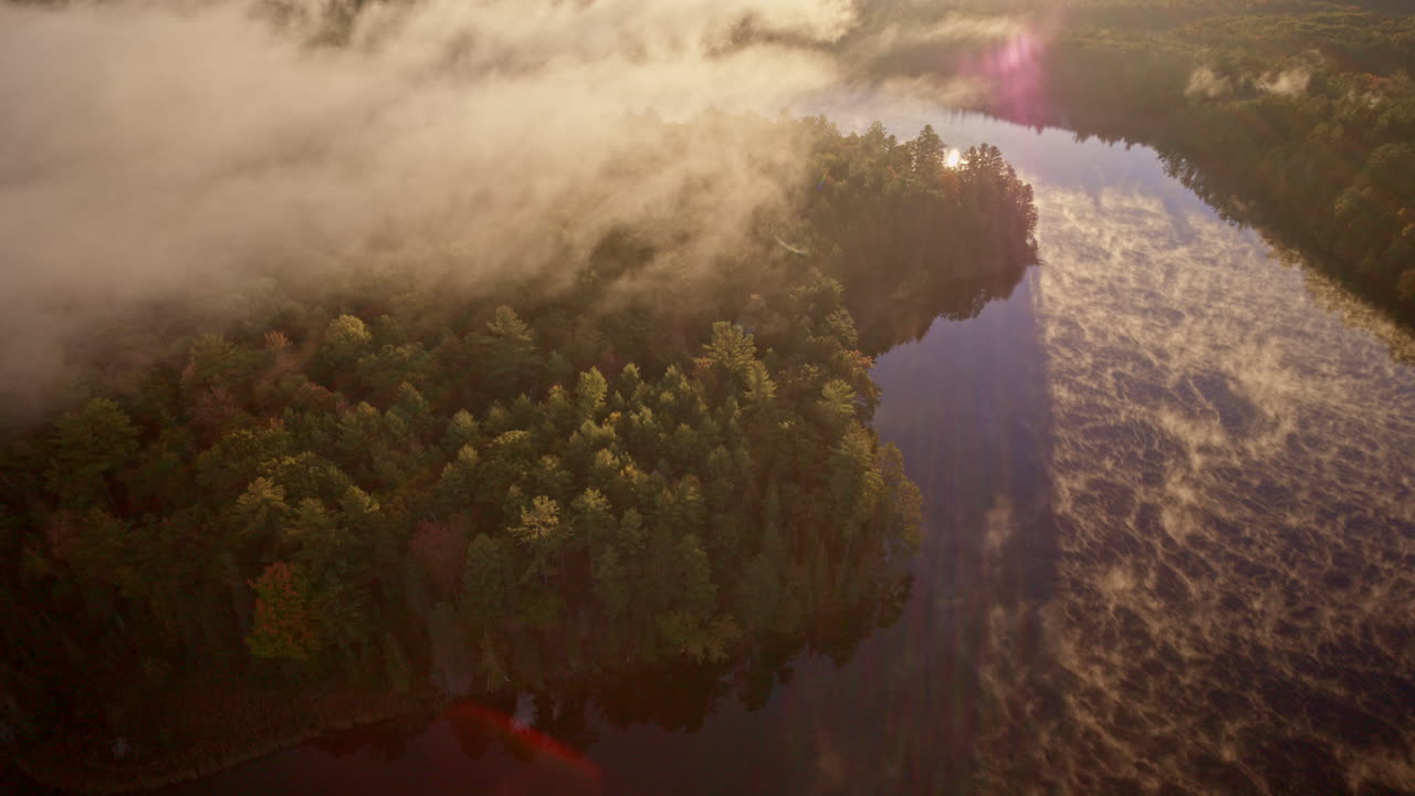 Aerial shot of faint morning mist rising from a calm water surface
