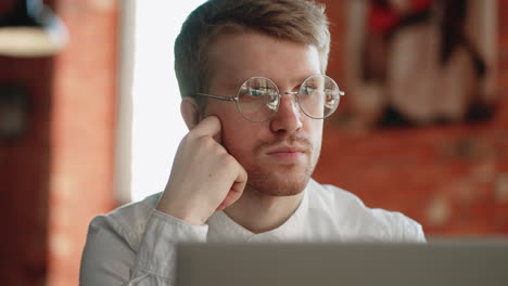 writer-or-journalist-is-sitting-in-cafe-with-laptop-portrait-of-pensive-face-with-glasses-freelancer-is-working