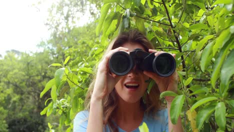 Lächelnde-Frau-Mit-Fernglas-Hinter-Blättern