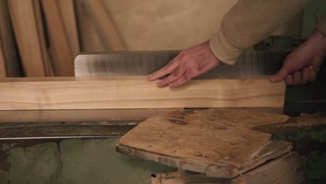 Man-in-overalls-polish-and-align-boards-with-electric-saw,-in-a-carpentry-workshop.-Slow-motion