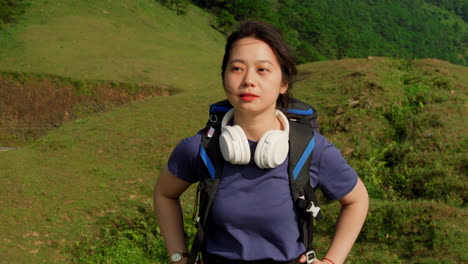 close up portrait slow motion of young asiatic female traveller backpacker with modern headphone walking in mountains hiking trekking path