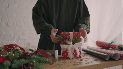 el envoltorio de regalo de una mujer joven y hermosa envuelve un regalo de navidad y lo decora con adornos decorativos ecológicos