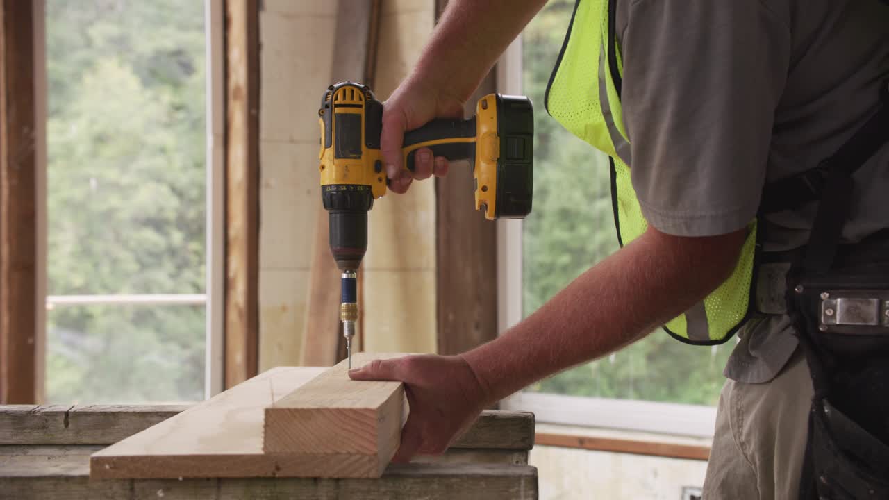 trabajador de la construcción que utiliza una pistola de tornillo inalámbrica
