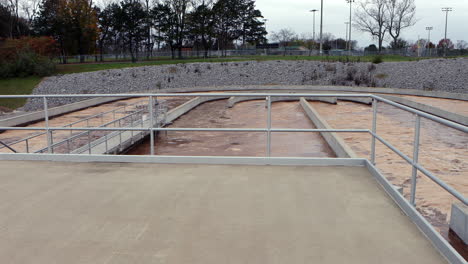 view from concrete platform of waste water aeration pools with foaming and flowing brown water