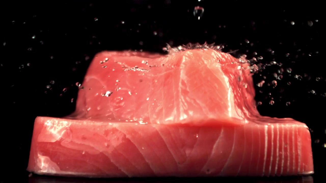 Acqua che schizza al rallentatore su filetti di tonno fresco crudo